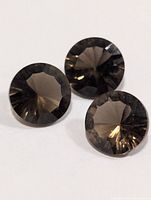 Three smokey quartz gemstones close-up showing faceting
