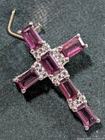 Front view of silver cross pendant with garnets and clear stones