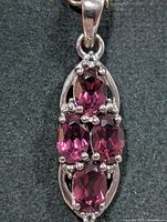 Front view of silver pendant showing four oval garnets and prong settings