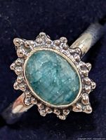 Front view of ring showing oval emerald and beaded halo