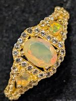 Front view of ring showing central oval opal, side opals and CZ halo