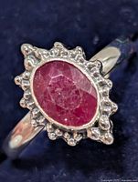Front view of sterling silver ring with oval ruby and beaded halo