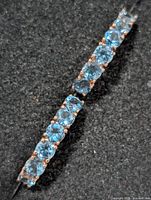 Close-up of row of seven blue topaz stones in silver setting
