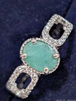 Top view of ring showing oval green stone and accent stones