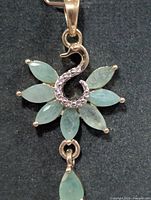 Front view of silver pendant with emerald flower and drop