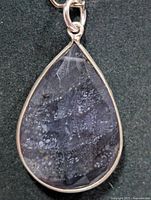 Front view of iolite teardrop pendant in silver bezel
