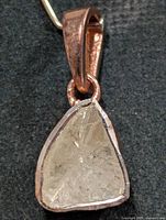 Front view of silver pendant showing rough triangular diamond and bezel