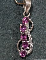 Front view of silver pendant showing four oval garnets and clear accent stones