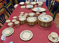 Stacked Lenox holly pattern plates, cups and saucers displayed on table