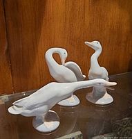 Three Lladró white porcelain duck figurines on shelf
