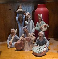 Group shot of six figurines and red vase