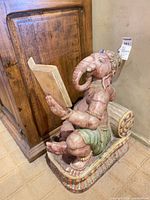 Left Ganesha statue reading a book against cabinet