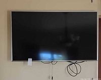 Front view of Samsung flat-screen TV mounted on wall with cables visible