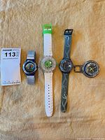 Group shot of four strapped watches and one watch head on fabric background