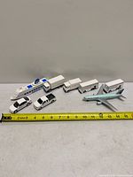 All eight toy vehicles lined up with measuring tape for scale