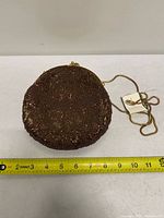Front view of bronze beaded circular clutch with tape for width