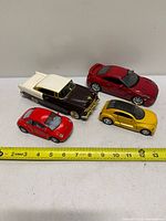 All four die-cast cars with tape measure for scale