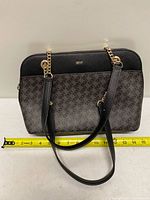 Front view of DKNY black and grey monogram tote with measuring tape showing width