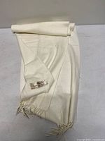 Full view of folded ivory cashmere scarf showing overall size and fringe