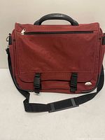 Front view of burgundy Samsonite messenger bag showing flap, buckles, shoulder strap