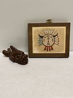 Sand painting plaque and carved wood animal figure side by side