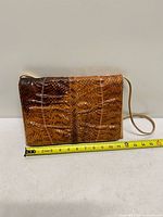 Front of clutch showing snakeskin flap and measuring tape indicating width about 11-12 inches