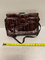 Front view of eel skin shoulder bag with measuring tape showing width