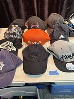 Group of assorted baseball caps on table