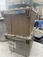 Two tan plastic storage totes stacked, showing sides and lids with wear