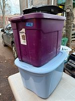 Purple and blue plastic totes stacked to show both colors, lids, and overall condition