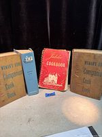All four cookbooks standing upright showing covers and spines