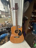 Full front view of Beaver Creek acoustic guitar leaning against doorway