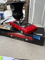 Red car-shaped VHS tape rewinder resting on its original box