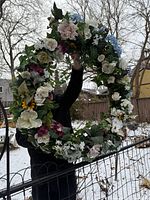 Front view of large floral wreath held outdoors showing full diameter and floral details