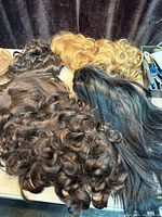 Multiple wigs in various colors laid out on table