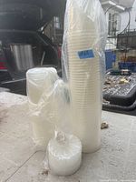 Plastic-wrapped stacks of assorted round translucent food containers and small lid bundle