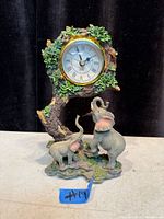 Front view of resin elephant clock showing tree, foliage, elephants, and clock face