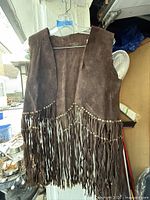 Front view of brown suede fringed vest on hanger