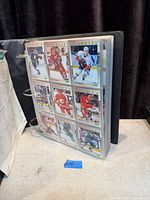 Album standing open showing nine hockey cards in plastic page