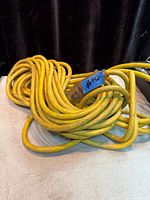 Coiled yellow extension cord with blue tape label visible