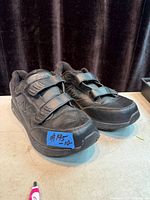 Side/front view of both shoes showing overall style, leather uppers, Velcro straps, and size note
