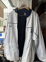 White woven side of reversible jacket displayed on hanger
