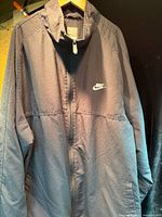 Front view of Nike jacket hanging, showing full garment and zipper