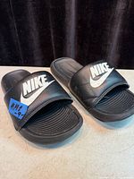 Top view of black Nike slide sandals showing strap logos and footbeds