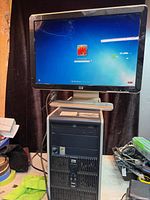 HP 19" monitor displaying Windows 7 login above HP tower