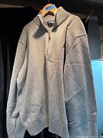 Front view of grey quarter-zip sweater on hanger