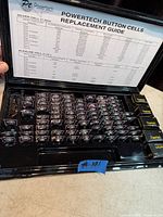 Opened display case showing large quantity of blister-packed Powertech button cells