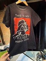 Full view of front of black Darth Vader "This Is My Happy Face" T-shirt on hanger