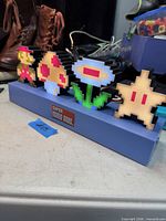 Front view of blue base night light with five pixel icons and Super Mario Bros. logo