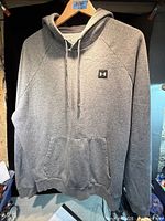 Front view of gray Under Armour pullover hoodie on hanger